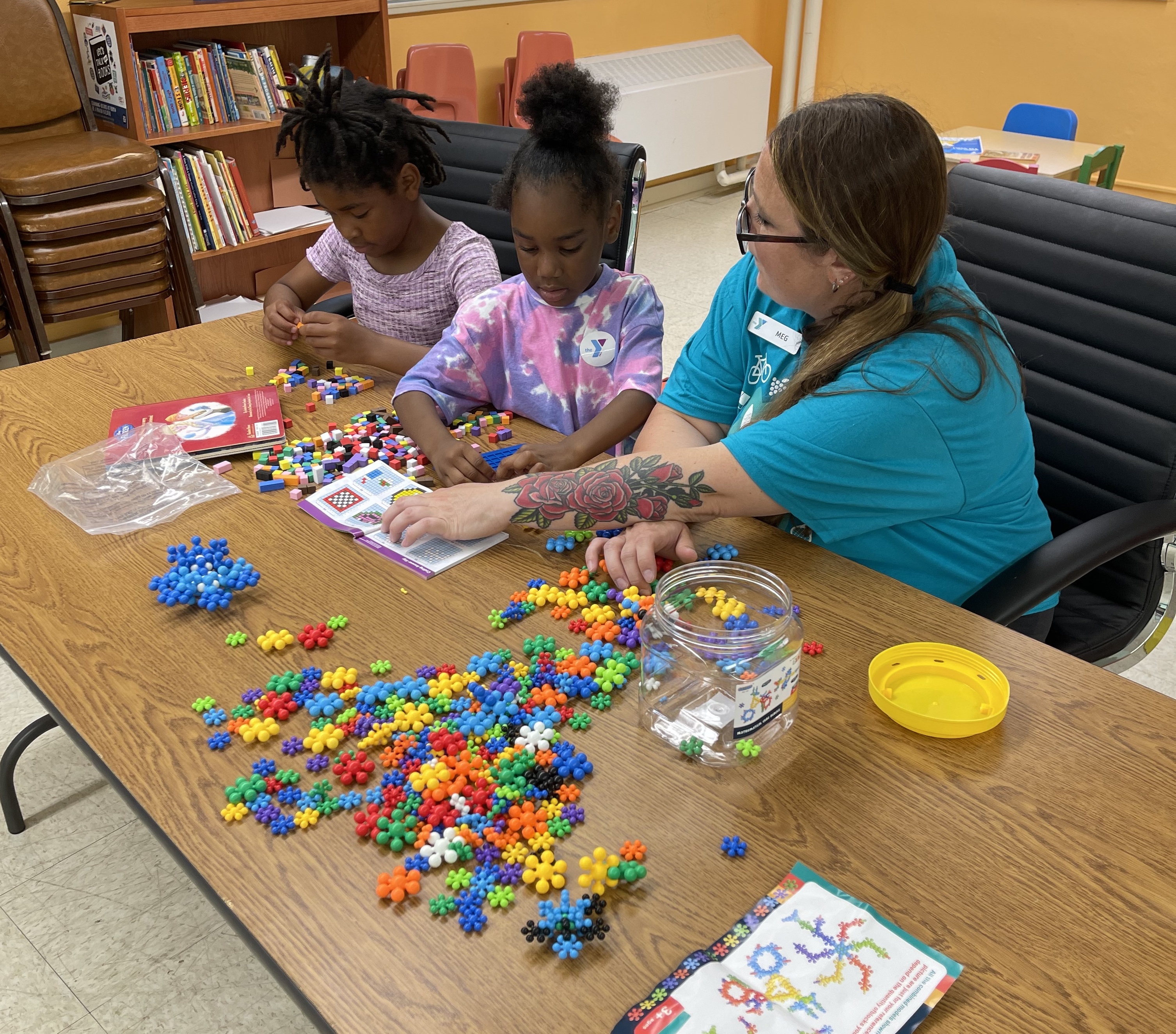 Y staff person sitting with two kids doing an activity