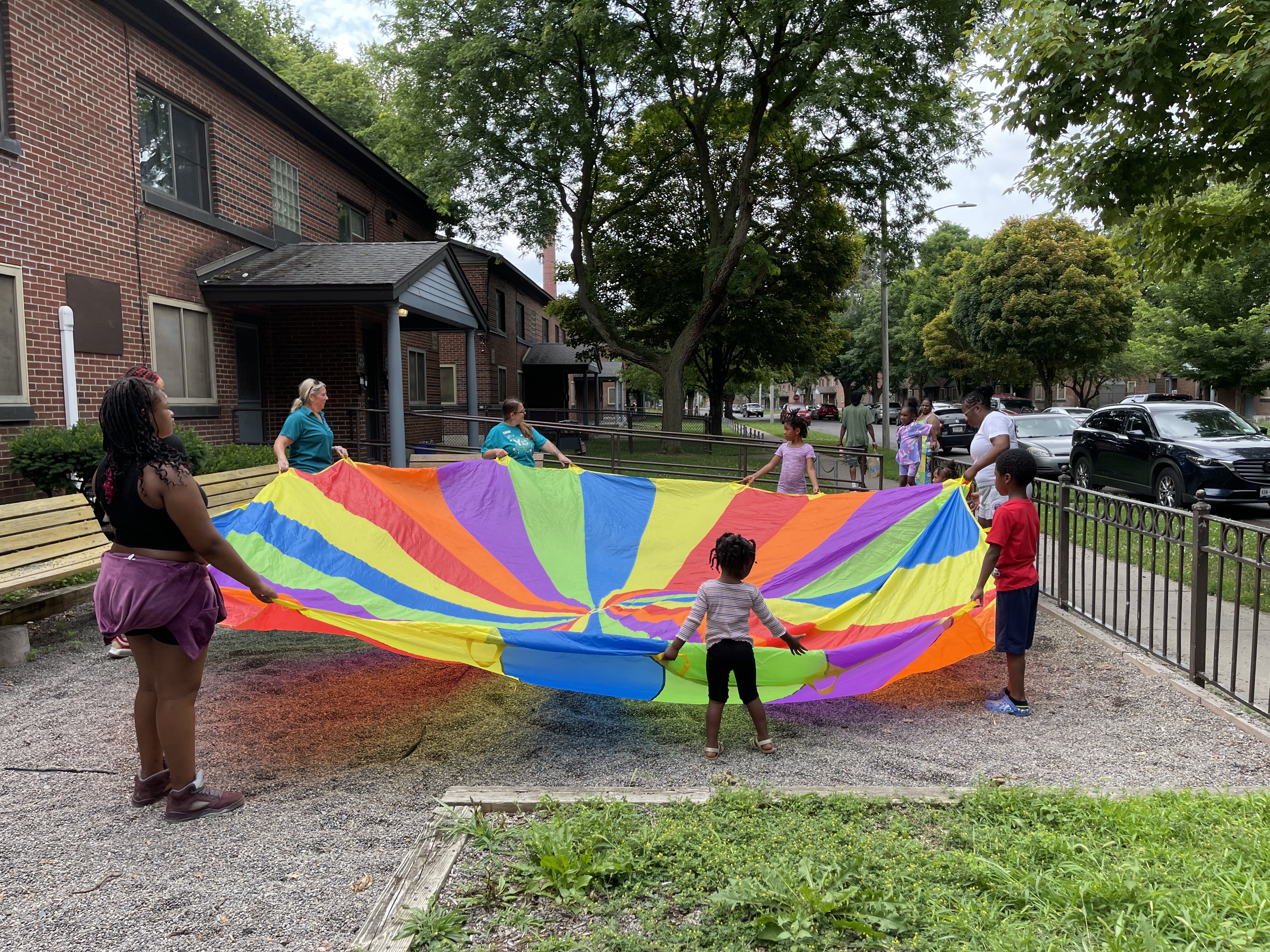 Y staff, kids, and families playing with a colorful parachute