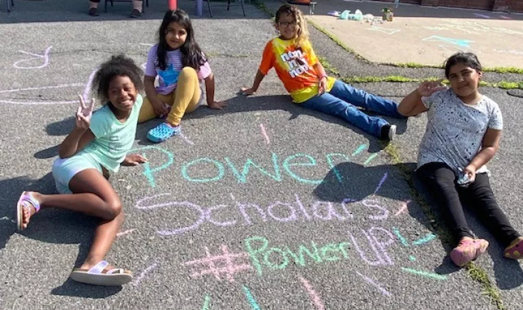 Four children sitting around chalk drawing
