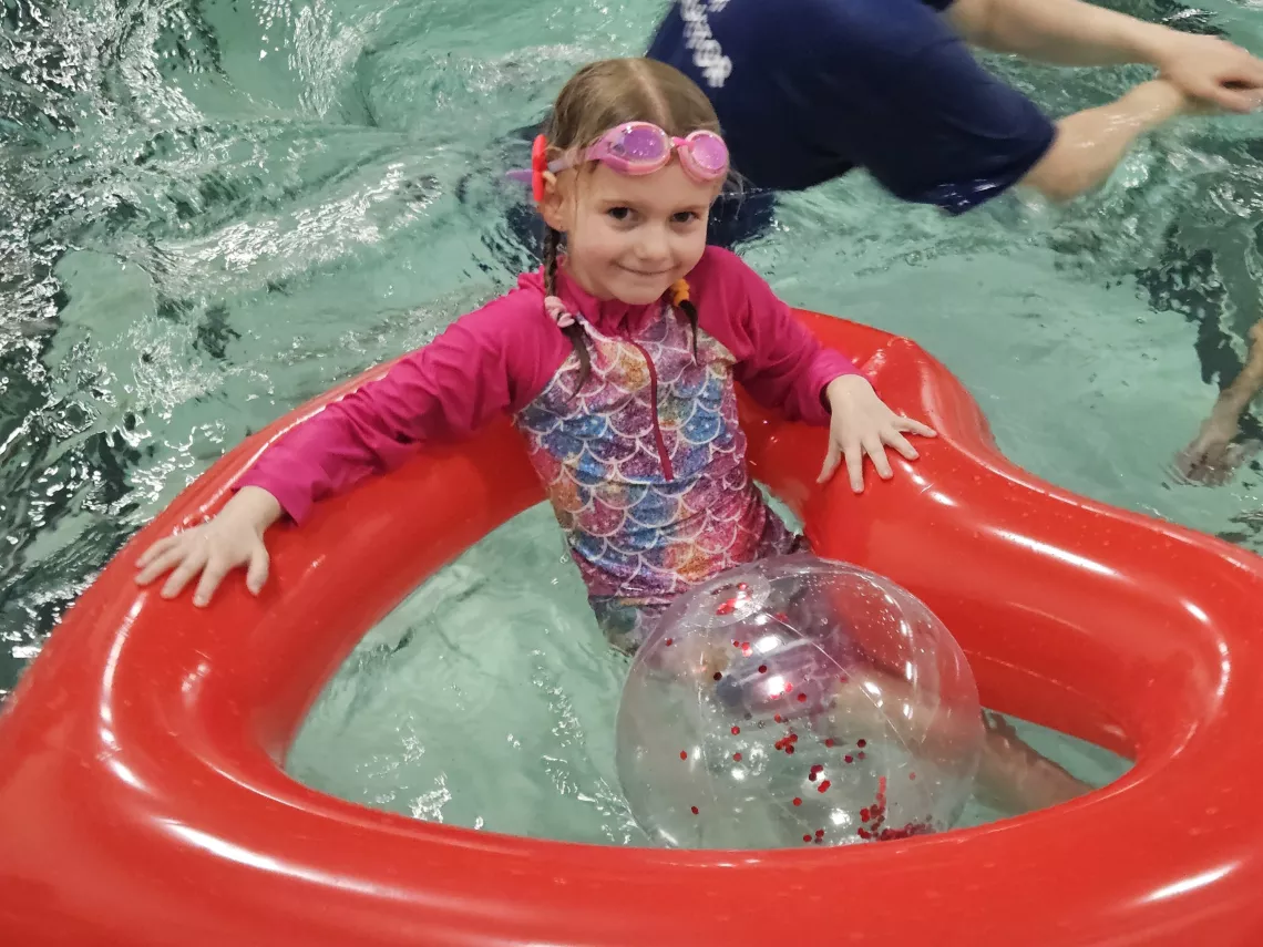 A child in a heart-shaped float in a pool