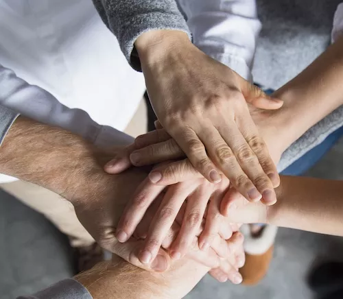 Hands coming together on top of each other in a circle