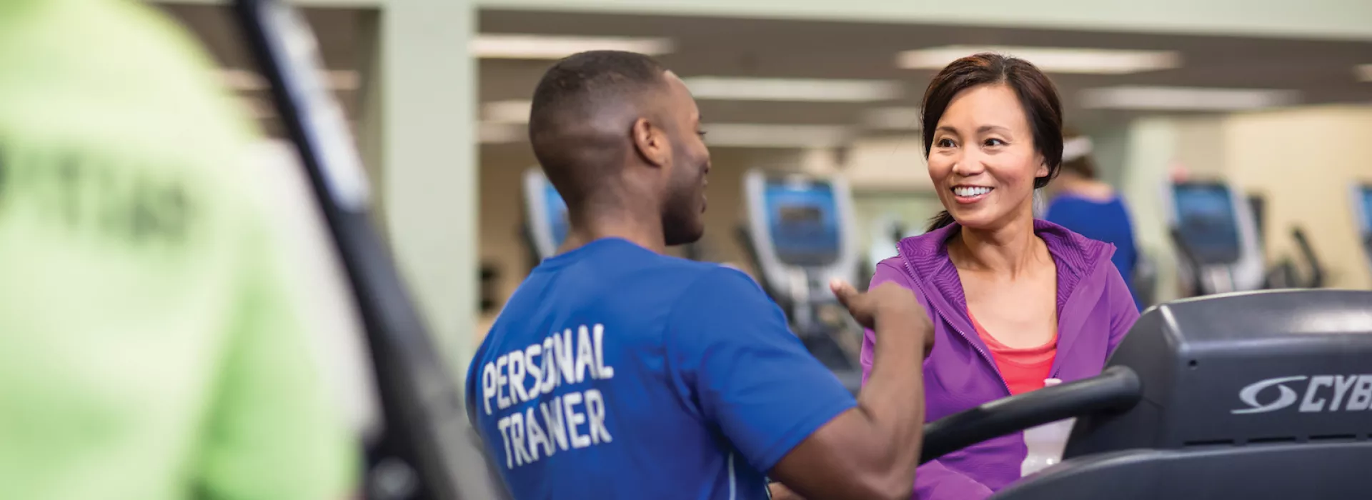Trainer talking to woman on treadmill