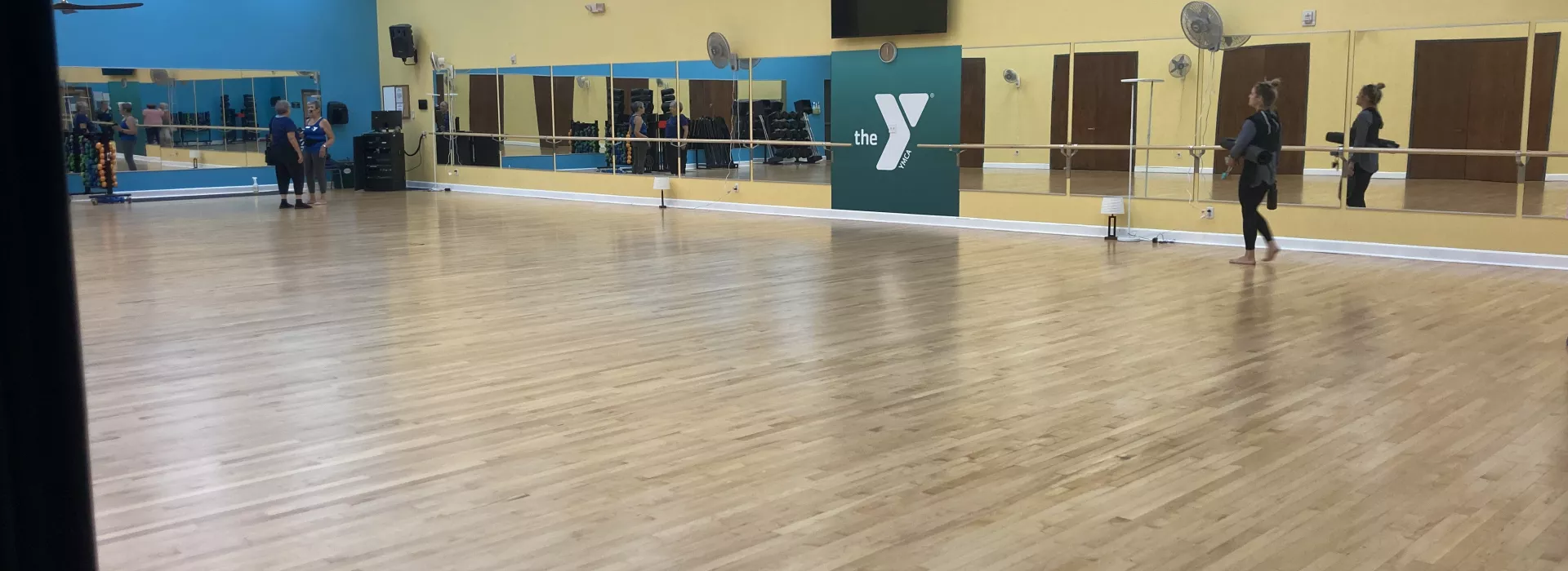 A large studio room for group exercise classes lined with mirrors