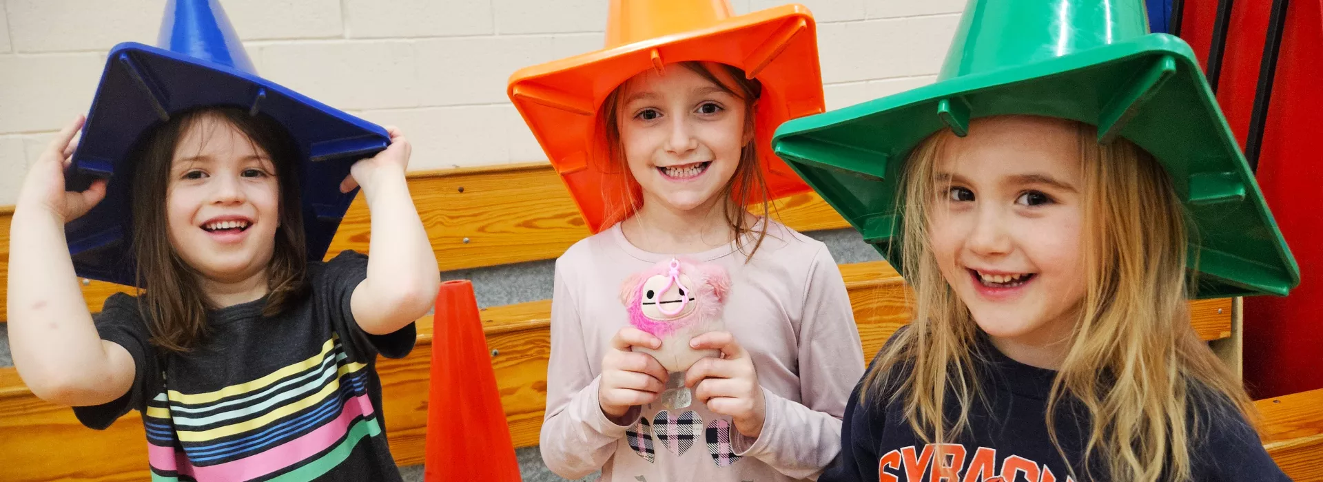 Trio of UPK kids smiling with cones on their heads.